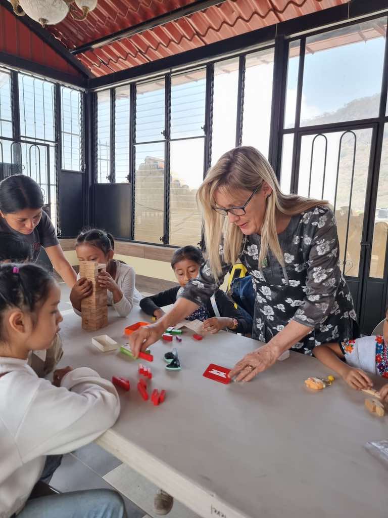 A group of children engaged in a playful learning activity at a table, featuring colorful toys and games in a bright, open space.