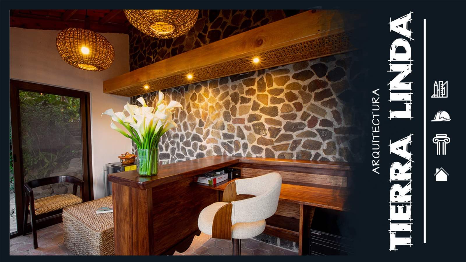 Cozy workspace featuring a wooden desk, modern chair, and a vase of white flowers against a stone wall backdrop, illuminated by warm lights.