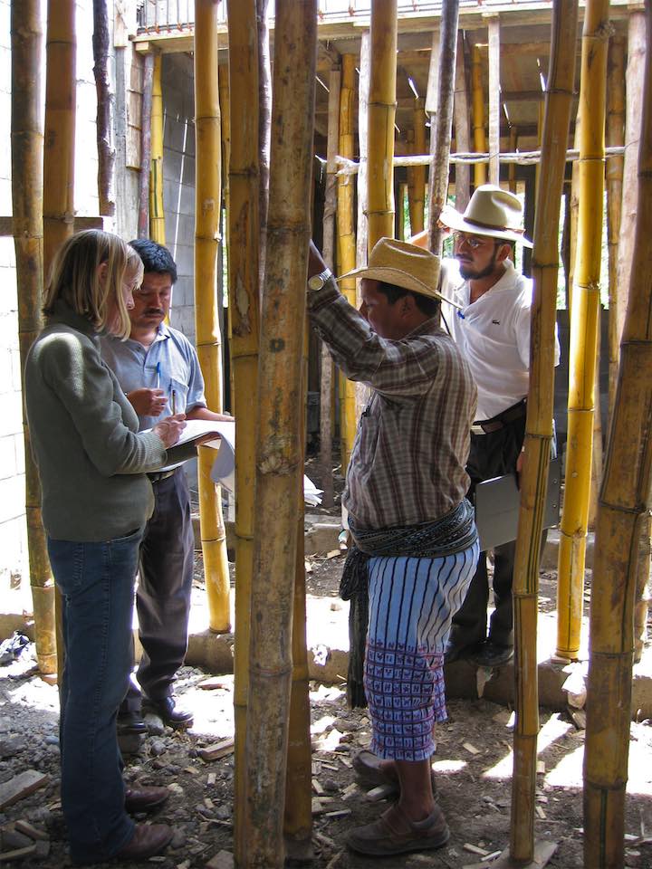 Molly Molander and crew gathered around at a building under construction, engaged in conversation and looking at the structure.
