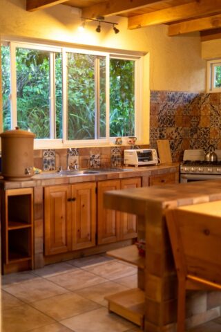 A cozy kitchen featuring a wooden table surrounded by four chairs, with warm lighting and a welcoming atmosphere.